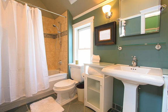 Guest Bathroom Remodeling with white vanity, bathtub, shower, and tiled walls.