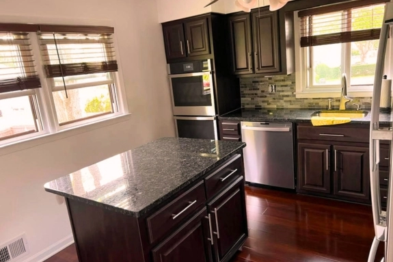 Kitchen remodeling with dark wood cabinets, granite countertops, and a center island in Beverly, NJ