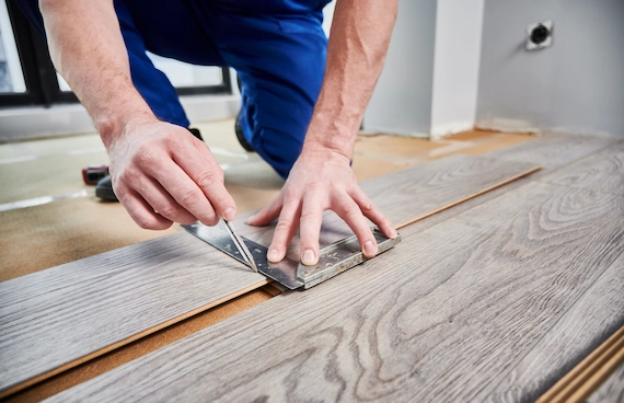 Professional Premium Wood Flooring Installation with a worker fitting wood-look flooring planks.