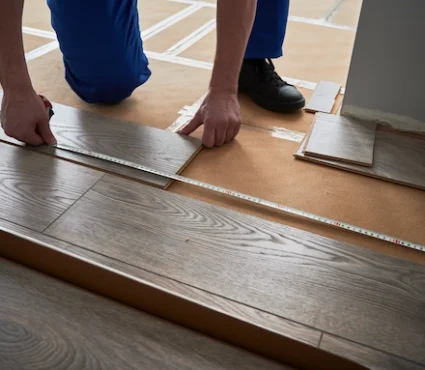 Professional Engineered Hardwood Flooring Installation with a worker fitting wood flooring planks.