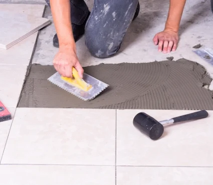 Professional Tile Flooring Installation with a worker applying adhesive for ceramic floor tiles.